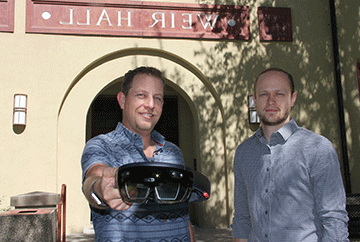 Ben Katko (right) and John Estry show the Microsoft HoloLens that they are using to create augmented reality tools for use in industry in the Senior Design Clinic. 